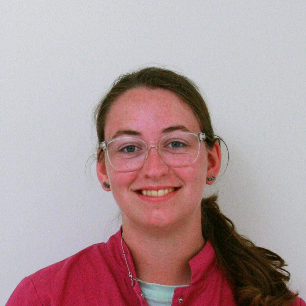 Portret van een medewerker van de kliniek met bril en roze werkkleding