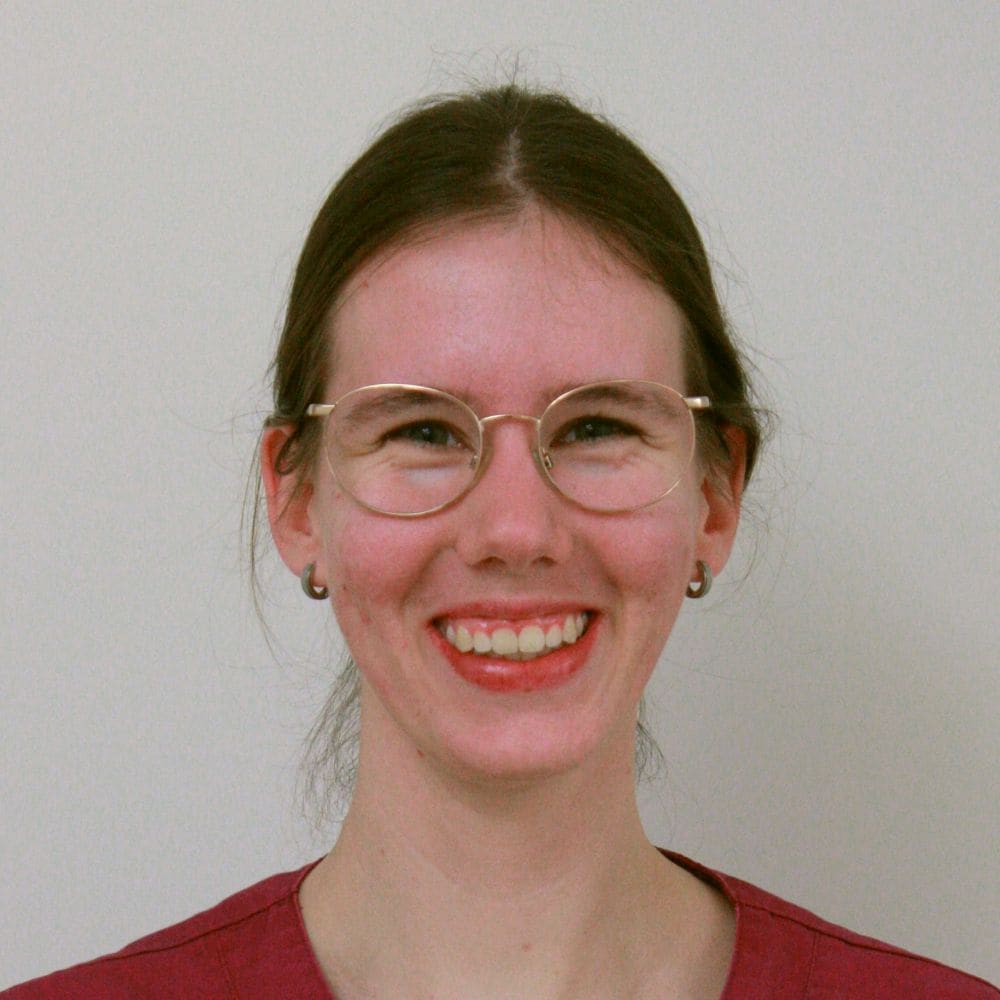 Portret van een medewerker van de kliniek met bril en rode werkkleding
